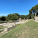 Olympia (Ολυμπία) - Ausblick von der Schatzhaus-Terrasse. Links ist das Metroon (Μητρώον) zu erahnen, hinten der Tempel der Hera (Heraion, Ηραίον), kurz davor der Altar der Hera in Olympia (Βωμός της Ήρας στην Ολυμπία), wo heutzutage die Flamme für die olympischen Spiele der Neuzeit entzündet wird. Rechts neben dem Altar befindet sich das Nymphaion (Νυμφαίο).
