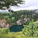 Ein erster Blick auf den Kratersee. Ob es noch bessere gibt? Dazu mussten wir ihn aber erst fast umrunden. Das dichte Buschwerk ließ sonst keine Sicht auf den See zu. Ein Maschendrahtzaun verhindert auch, dass man zu nah an die Abbruchkante herankommt. 
.
Bis 1979 wurde hier Basalt abgebaut. Der [https://www.hikr.org/gallery/photo564265.html?post_id=39126 Hohenstoffeln] wurde früher ebenfalls durch Basaltabbau im Gipfelbereich "angeknabbert" und seine Kegelform dadurch deformiert.
