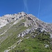 Entlang der Gratschneide, links Gras, rechts Fels, geht es auf die Felsen zu.