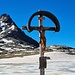 <b>Ad un chilometro e mezzo di distanza, sulla riva settentrionale del Lago Bianco (2606 m), mi fermo a fotografare un crocifisso ligneo. <br />L’artistico manufatto venne fatto apporre in questa posizione da un giovane in segno di ringraziamento per essere riuscito a sopravvivere ad un’improvvisa bufera di neve che lo colse di sorpresa mentre transitava con l’auto dal Passo con la moglie e la madre.<br />Usciti miracolosamente indenni dalla tormenta i tre viandanti riuscirono a raggiungere l’abitato di Ponte di Legno senza alcuna conseguenza. L’accaduto, avvenuto il 2 ottobre del 1929, spinse il giovane ad erigere questo grande crocifisso votivo in segno di gratitudine per lo scampato pericolo.</b><br />