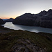 Aufstieg in der Dämmerung zu Le Clocher: über dem Lac des Dix links der Mont Blava, über der Staumauer der Pic d'Artsinol, dazwischen hinten der Wildstrubel, in der Mitte die Poine de Vouasson, rechts die Aiguilles Rouges d'Arolla