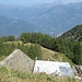 Vista dall’Alpe Pozzolo verso valle, dove si vede il rifugio (nel cerchietto giallo) e la Val d’Ossola; chiude il panorama il Monte Leone.