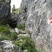 Der Klettersteig beginnt mit einer Leiter aus in den Felsen geschlagenen Metallbügeln, hinten an der Felsstufe.