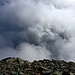 Vom Pass aus ein gutmütiger Rücken, fällt der Gipfel nach der anderen Seite steil ab. Wilde Wolken...