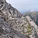 Links geht noch der Weg hoch zum Gipfel, am Pfeil beginnt der geröllige Teil der Überschreitung, nach dem man bereits ca. 30 Meter ab und aufgestiegen ist.