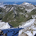 Tiefblick von der Brèche de Séraukin zur kurzen Krete und zu den Chalets de Bise, darüber die Pointe de Bénévent, dahinter u.a. die Pointe de Pelluaz, nach rechts und vorübergehend im Grünen geht der Weiterweg zum Col de Bise, links davon der Saix de Bise, dahinter Roc de Château und Dent d'Oche, am Horizont über dem Lac Léman der Neuenburger und Waadtländer Jura