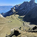 Tiefblick vom Kreuz über die Gipfelflanke hinunter zur Rippe, an deren linkem Rand (im Schatten) der weitere Abstieg erfolgt. Unten Lovenex und der Lac de Lovenex, darüber von rechts Mont Gardy, Mont Valeur, Le Grammont, Pointe de Chaumeny und Rocher de la Croix, links über dem Lac Léman Motreux und die Préalpes