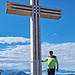 Älterer Bergwanderer am neueren Gipfelkreuz