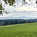 ... schönen Blicks über die Hochebene namens "Rangen" ("Ranga" im hiesigen Dialekt). Das nun breit gewordene Plateau des Bergrückens wird ab hier landwirtschaftlich mit Ackerbau und Weidewirtschaft genutzt und beherbergt sehr kleine Dörfer und Einzelgehöfte. Blick am waldrandig gelegenen Aussichtspunkt Kesselleithe bis herüber zum Fichtelgebirge.