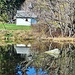 Die Hubertuskapelle spiegelt sich im Weiher.<br /><br />Auf Bänken neben der Kapelle sitzen Sonnenhungrige am Waldrand. Auf Bänken am Waldrand oder im Wald zu sitzen, könnte in Baden-Württemberg bald ein Ende finden. Zwei Gemeinden in Baden-Württemberg haben Bänke im Wald bereits abgebaut, da sie das Haftungsrisiko herunterfallender Äste nicht tragen wollen (Bericht im SK vom 04.11.2024). Armes Deutschland kann man da nur sagen!