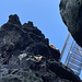 Im Aufstieg zur Mariina skála - Blick aus einer kleinen Schlucht auf eine steile Metalltreppe, die zum Gipfel führt.