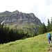 Auf dem Bandweg. Nach der flachen Wiesen-/Sumpfpassage führt der Weg steil bis unter die Felswand aufwärts, dann nach rechts über das untere Band der Felswand entlang und schliesslich wieder nach links der Oberkante der Felswand entlang.