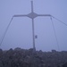 Gipfelkreuz mit einprägsamem Spruch im Nebel