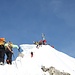 <b>Arrivo al deposito sci alle dieci circa. È talmente affollato che trovo a fatica un posto dove conficcare gli sci nella neve. Per raggiungere la vetta devo percorrere ancora un affilato tratto di cresta di circa 70 m. Mi aiuto con i bastoncini telescopici: è evidente che in caso di scivolata questi non sono di grande aiuto. Sarebbe più saggio percorrere questo tratto terminale con una piccozza o con i ramponi.</b>