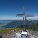 Gipfelkreuz mit Schatulle des Gipfelbuches auf dem Fronalpstock. Im Hintergrund Mattstock (rechts vom Kreuz) und Speer (gerade verdeckt vom Kreuz).