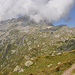 Rechts Albrunpass mit vierschrittigem Schneeflecken, links versteckt in den Wolken der Albrunhorn/Monte Figascian.