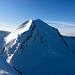 Der schneeweisse Castor vom Pollux aus gesehen. Der Aufstieg erfolgt über die schattige Westflanke (eine Seilschaft am Einstieg ist zu erkennen)