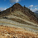 Die Gipfelspitze des Piz Traunter Ovas mit den farbigen Gesteinsbändern im Vordergrund.