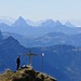 [u Lena] beim Gipfelkreuz, aufgenommen vom höchsten Punkt am Federispitz. Dominant treten die Mythen in Erscheinung.