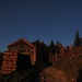 Forsthüttn "Brunnenkopf-Diensthütte" 1570 m am Sattel vor den Brunnenkopfhäusern, noch mit Mond. Hier kann man erstmals auf dem Grat am Reitweg nach Norden hinunter ganz weit ins Alpenvorland schauen. Geradeaus vor uns das Gipfelkreuz des Brunnenkopfs, der auf einem Weg vom Wirtshaus abzweigend bestiegen werden kann.