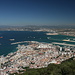 Gibraltar - Ausblick von der Aussichtsterrasse nahe der Cable Car Top Station (Seilbahn-Bergstation) in nordwestliche Richtung. Unten: Gibraltar u. a. mit Hafen (links) und dem Westteil der Start- und Landebahn des Flughafens (rechts). Etwas nördlich davon (dahinter) befindet sich bereits die Grenze zu Spanien. 
