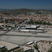 Gibraltar - Ausblick aus der Nähe des Ausgangs aus den Great Siege Tunnels u. a. zum Flughafen von Gibraltar. Gut erkennt man, wie die Start- und Landebahn von der vierspurigen Straße gekreuzt wird, welche die City mit dem Grenzübergang zu Spanien verbindet. Im Hintergrund ist La Línea de la Concepción zu sehen.