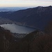 Tiefblick von der Waldlichtung auf 1200m über den Monte Sant'Agata (940m) auf Melano (293m) und den Lago di Lugano (271m).

Am Seeende ist Riva San Vitale (273m) und der Berg am anderen Seeufer ist der Monte San Giorgio (1096,7m).