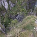 Der Auf- und Abstieg verläuft über einen steilen Felsaufschwung, der vom Felstor (weißes Zeichen in der Bildmitte) zur Kante rechts hinaufzieht