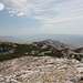 Gipfelbereich Dinara - Teilpanorama 5/10. Ausblick in Dunst und Gegenlicht in etwa südliche Richtung. Zu erahnen sind u. a. der Stausee Perućko jezero und das westlich davon (rechts) gelegene Svilaja-Gebirge.