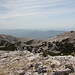 Gipfelbereich Dinara - Teilpanorama 6/10. Ausblick in Dunst und Gegenlicht in etwa südliche/südwestliche Richtung. Im Hintergrund ist das Svilaja-Gebirge zu sehen, links ist der Gipfel des Svilaja (Bat), 1.509 m, samt Nachbarkuppe zu erahnen. Der Kozjak (Bat), 1.205 m, zeichnet sich an den nordwestlichen Ausläufern der Bergkette schon etwas deutlicher ab (rechts der Mitte).