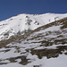 Ein kurzes Stück muss wegen Schneemangel wieder mit den Schi auf dem Rücken bewältigt werden; rechts hinten sieht man schon den Gipfel