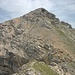 Der Übergang führt hinunter in die Scharte. Jenseits werden die im Bild gut sichtbaren Felsen unterhalb umgangen, dahinter geht's die Schuttflanke zum Gipfelaufbau hinauf; der Gipfel wird von links nach rechts erstiegen.
