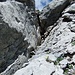 Vor dem horizontalen Kamin: steiler Aufstieg bis zum Felsblock. Dann rechts auf Knien oder robbend einer schmalen Leiste entlang unter dem Block durch.