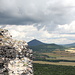 Oltářík/Hrádek - Ausblick in etwa nördliche Richtung zu den noch schattigen Gipfeln von Milešovka (mittig) & Co. Links sind Teile der Burgruine am Oltářík-Gipfel zu sehen.