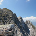 Im Aufstieg vom Grauspitzsattel zum Grauspitz - Blick im Gegenlicht zu den steilen Abbrüchen auf der Liechtensteiner Seite. Ganz links oben ist der Vorgipfel, daneben der Hauptgipfel des Grauspitz zu sehen.