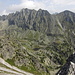 Predné Solisko - Ausblick vom Gipfel auf den Bergkamm Hrebeň Bášt mit dem Satan. Unten im Tal Mlynická dolina sind der Bergsee Pleso nad Skokom und rechts daneben die Geländestufe mit dem Wasserfall Vodopád Skok zu sehen.