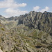 Predné Solisko - Teilpanorama 2/12. Ausblick zu Štrbský štít (2.381 m, hinten links) und auf den Bergkamm Hrebeň Bášt mit dem Satan. Unten ist der Bergsee Pleso nad Skokom zu sehen.