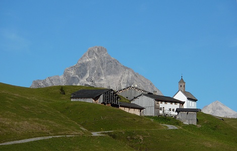 das weißgekalkte Kirchlein mit der Handvoll Holzhäuser der alten Walsersiedlung Bürstegg 1710m ist zu sehen
