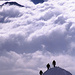 Eine Seilschaft am steilen Ostgrat des Piz Palü. Aus dem Wolkenmeer im Hintergrund ragen einige Gipfel der Bergamasker Alpen hervor. Fotografiert vom Ostgipfel des Piz Palü (3882m).