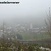 Nebelverhangen liegt die kleine Ortschaft unter uns