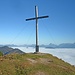 Gipfelkreuz über den Wolken; rechts vom Kreuz der markante Guffert.