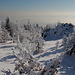 Unterwegs am Pramenáč - Hier zur nahe des Gipfels gelegenen Felsformation. Der Ausblick über die herrliche Winterlandschaft lässt in Gegenlicht und Dunst die Silhouetten der Bergkegel des České středohoří (Böhmisches Mittelgebirge) gerade noch erahnen.
