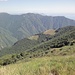 Blick von der Colma di Belmello zur Alpe Leciurt. Der Abstieg nach Pogallo führt durch den Wald unterhalb der Alp nach links unten.